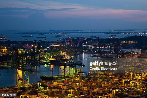 Stacked containers sit among gantry cranes illuminated at dusk at Tanjong Pagar Container Terminal, operated by PSA International Pte, at the Port of...