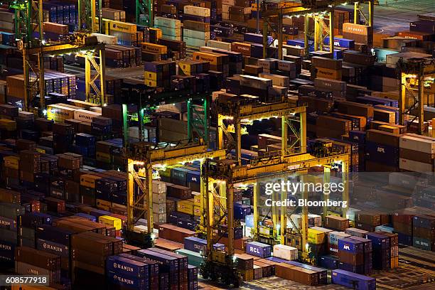 Stacked containers sit among gantry cranes illuminated at night at Tanjong Pagar Container Terminal, operated by PSA International Pte, at the Port...