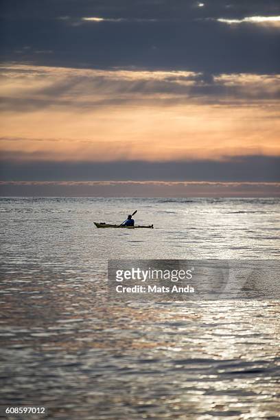 man kayaking in sunset in lofoten, norway - zeekajakken stockfoto's en -beelden