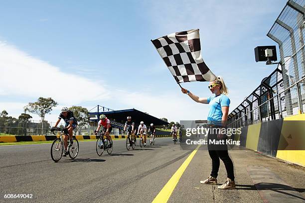 Kaarle McCulloch waves the chequered as cyclists finish the marathon race during the 2016 Below The Belt Pedalthon at Sydney Motorsport Park on...