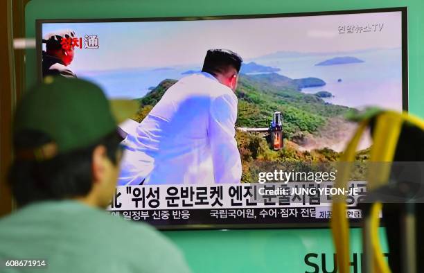 Man watches a television news report showing North Korean leader Kim Jong-Un looking at the country's latest ground test for a rocket engine, at a...