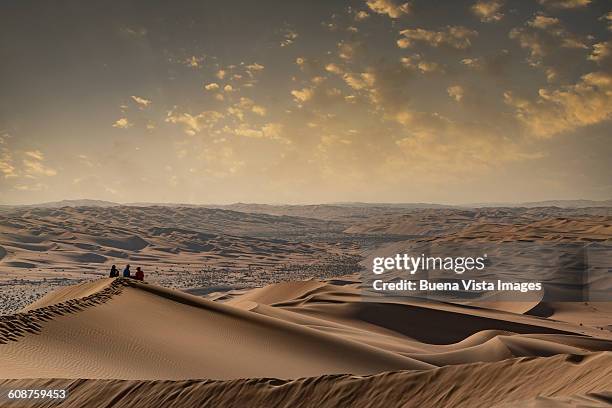 family on a sand dune watching sunset - abu dhabi people stock pictures, royalty-free photos & images