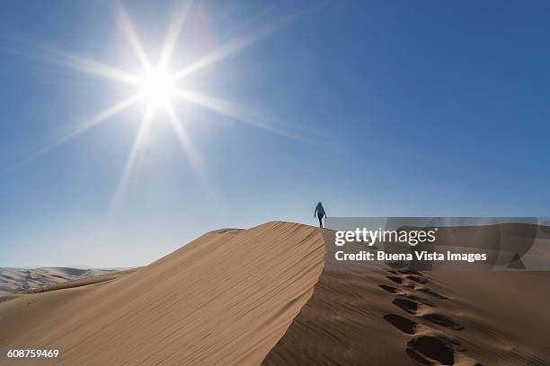 woman climbing a giant sand dune in a desert - voetstappen stockfoto's en -beelden