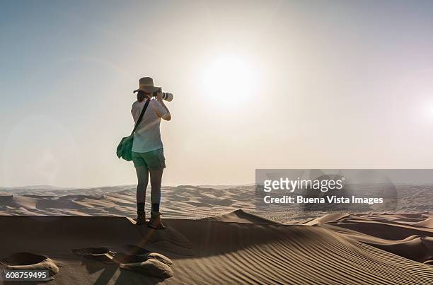 woman on a sand dune taking pictures of sunset - hot arabian women stock pictures, royalty-free photos & images