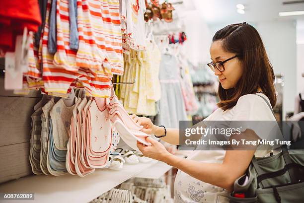 pregnant lady shopping for baby items joyfully - baby clothing stock pictures, royalty-free photos & images