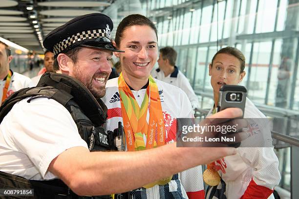 Gold medallist Sarah Storey poses for a selfie with a police officer after arriving on British Airways flight BA2016 from Rio de Janeiro to London...