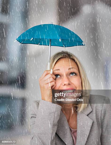 blonde woman in the rain with tiny umbrella - nat stockfoto's en -beelden