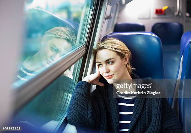 young woman on a train looking out the window - train vehicle stock-fotos und bilder
