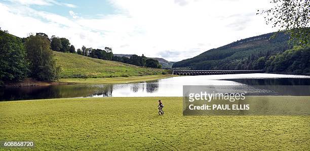 Jon Rae rides his mountain unicycle around the edge of Derwent Reservoir in Derbyshire, central England, on September 20, 2016. / AFP / PAUL ELLIS