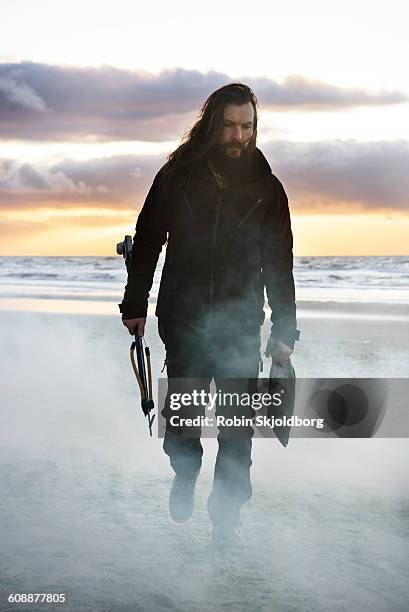 man with fish and speargun walking on beach - arpón fotografías e imágenes de stock