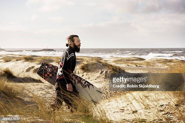 man with kitesurf board walking on beach - kiteboarding fotografías e imágenes de stock