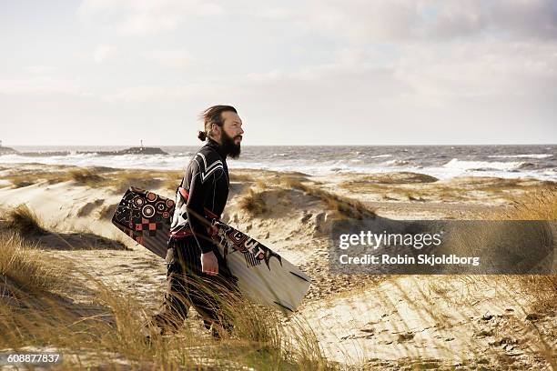 man with kitesurf board walking on beach - kite surfing stock pictures, royalty-free photos & images