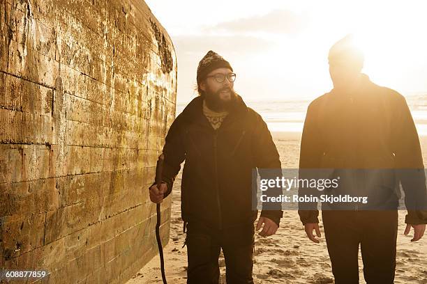 men walking next to bunker on beach - hvide sande denmark stock pictures, royalty-free photos & images