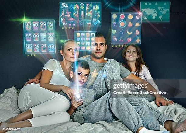 family browsing apps and games in their bed - boy in pajamas and mom on tablet stock-fotos und bilder