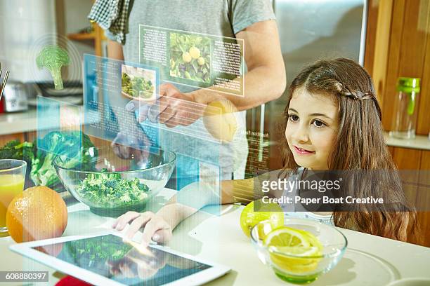 daughter looking at holograms of recipes on tablet - familie technologie virtuell stock-fotos und bilder