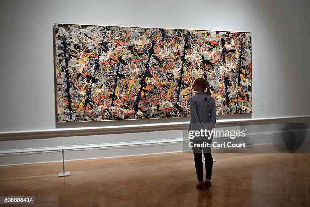 Member of staff poses next to a painting by U.S artist Jackson Pollock entitled 'Blue Poles' at the Royal Academy of Arts on September 20, 2016 in...