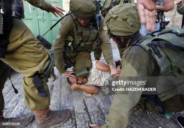 Israeli soldiers restrain a Palestinian man as troops try to arrest him in the flashpoint city of Hebron, in the Israeli-occupied West Bank, on...