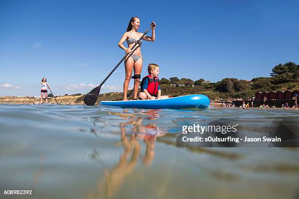 family stand up paddleboarding on the isle of wight. - isle of wight stock pictures, royalty-free photos & images