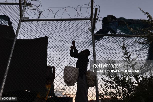 Migrants fix their makeshift tent made from blankets in the Moria camp, on the island of Lesvos, on September 20, 2016. Thousands of migrants were...