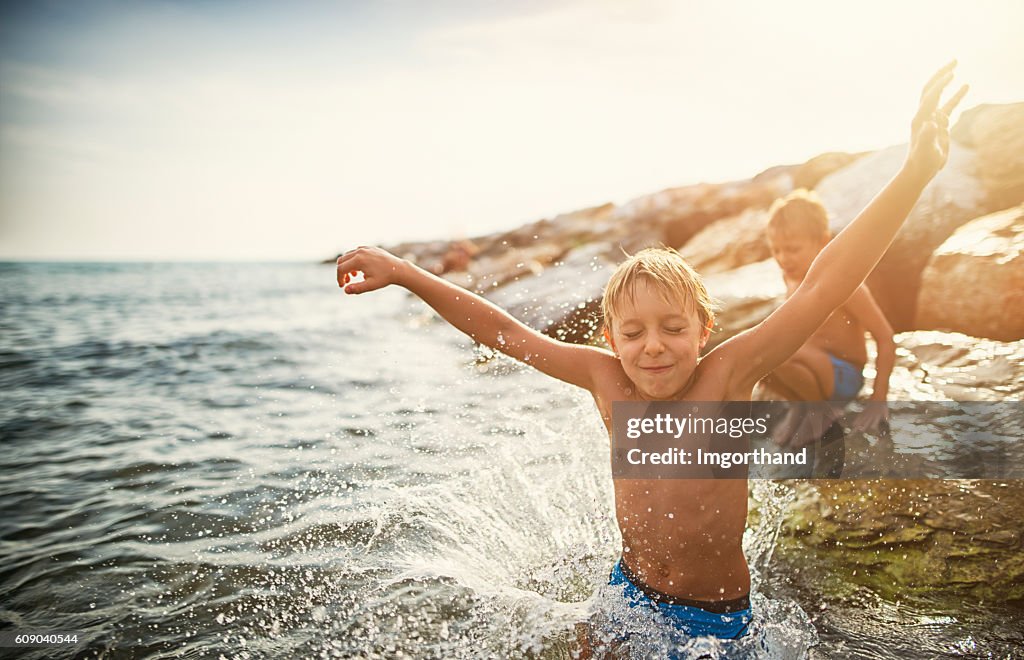 Kids jumping into the sea from big stones