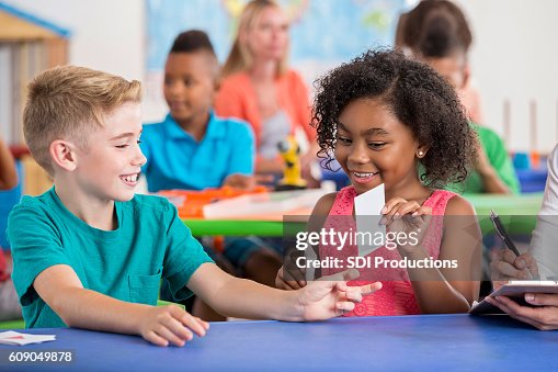 Two elementary age students using flashcards during class Two elementary age students using flashcards during class