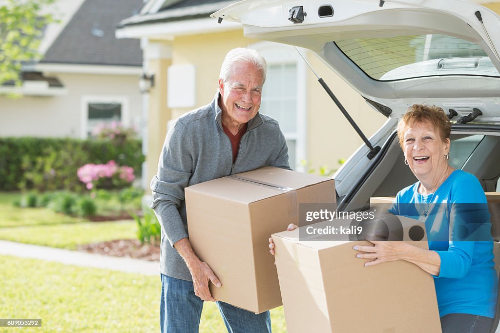 Happy senior couple moving boxes in car