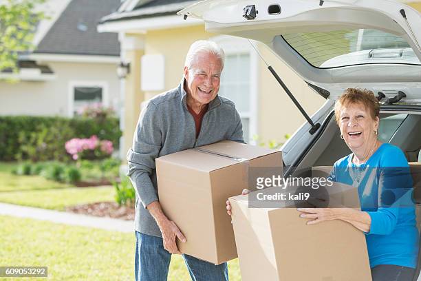 happy senior couple moving boxes in car - omstrukturering bildbanksfoton och bilder