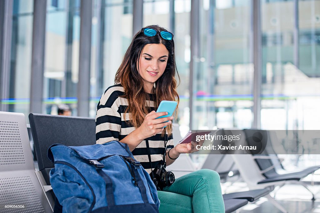 Woman with backpack and mobile phone waiting for boarding