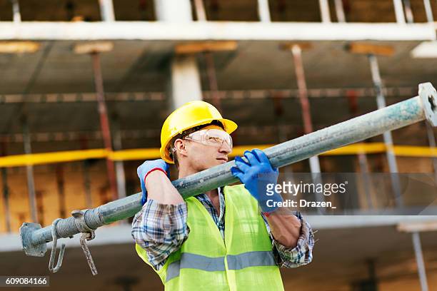 worker carrying steel support bars on construction site - man muscular build stock pictures, royalty-free photos & images