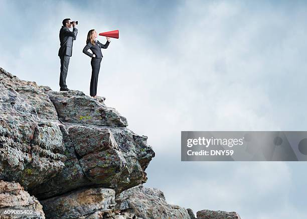 homme d’affaires et femme d’affaires essayant de communier tout en se tenant sur cliff - paire de jumelles photos et images de collection