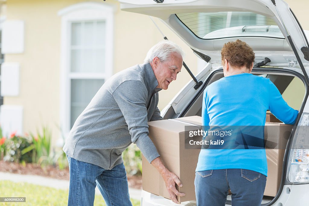Senior couple moving boxes in trunk of car