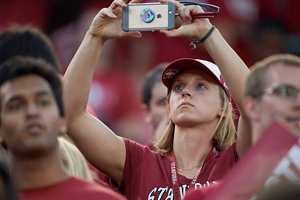 Olympic Gold medalist and Stanford swimmer Katie Ledecky taking picture with camera phone in stands during game vs USC at Stanford Stadium. Stanford,...
