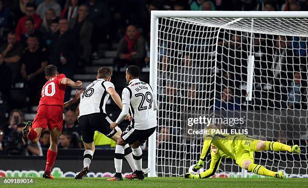 Liverpool's Brazilian midfielder Philippe Coutinho scores their second goal as Derby's English goalkeeper Jonathan Mitchell dives across his goal...