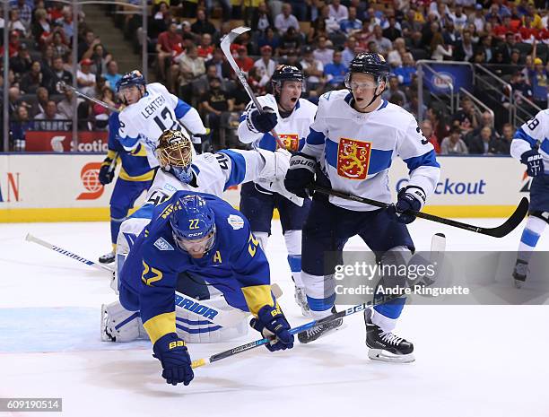 Daniel Sedin of Team Sweden gets knocked to the ice in front of Tuukka Rask and Olli Maatta of Team Finland during the World Cup of Hockey 2016 at...