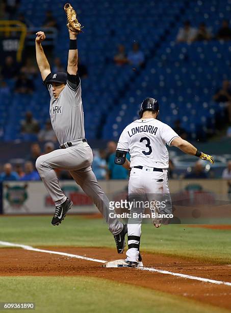 Evan Longoria of the Tampa Bay Rays reaches first base ahead of first baseman Mark Teixeira of the New York Yankees on an infield single to third...