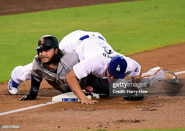 Brandon Crawford of the San Francisco Giants reacts after he is tagged out at third base by Corey Seager of the Los Angeles Dodgers to end the top of...