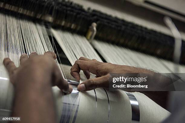 Worker manually inspects thread tension on a loom at D.L. Nash Ltd., a textile manufacturer in Karachi, Pakistan, on Saturday, Sept. 10, 2016....