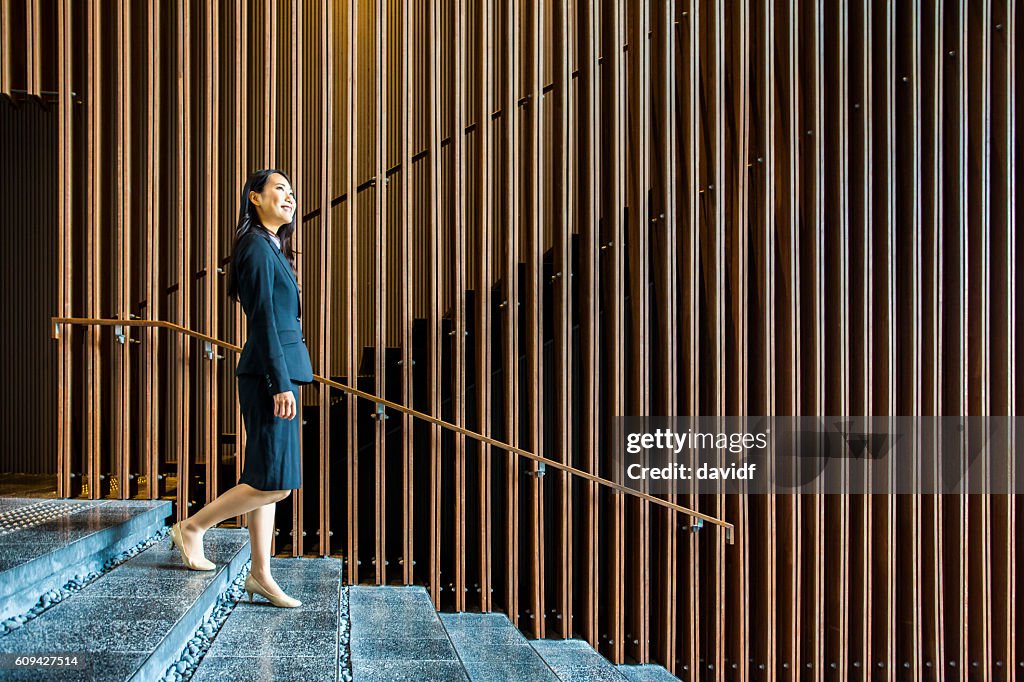 Femme d’affaires japonaise professionnelle marchant dans les escaliers dans un hall de bureau
