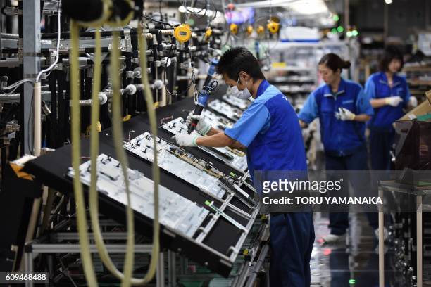Workers assemble LCD 4K televisions on an assembly line at the Utsunomiya Plant of Japan's electronics giant Panasonic in Utsunomiya, 100 kilometres...