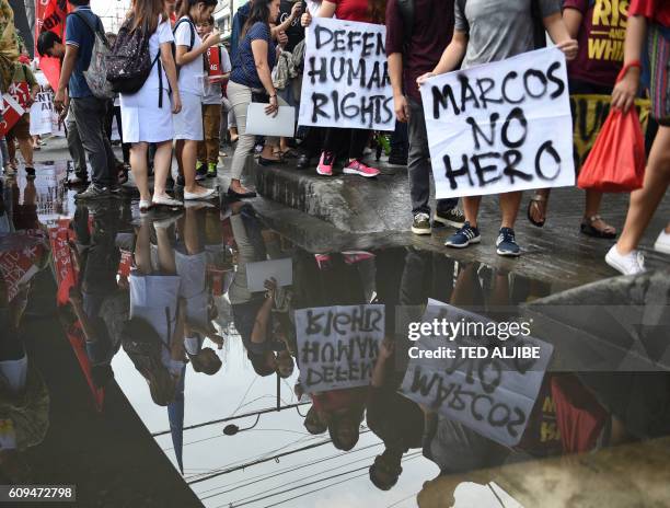 Activists holding placards are reflected on a temporary pond as they march to commemorate the 44th anniversary of the declaration of martial law by...