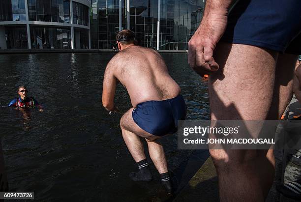 Blind or visually impaired demonstrators take a swim in the river Spree in front of the Reichstag building which houses Germany's Bundestag lower...