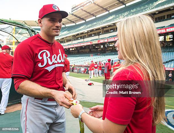 Joey Votto of the Cincinnati Reds talks with olympic gold medalist Courtney Mathewson of the United States women's water polo team while looking at...