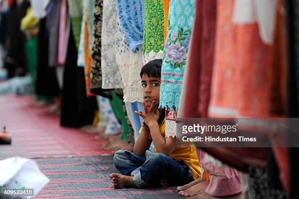 Kashmiri boy looks up as Kashmiri women offer prayers at the Hazratbal Shrine on September 21, 2016 in Srinagar, India. People are holding special...