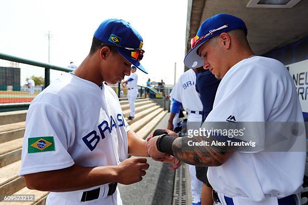 Gabriel Maciel and Lucas Rojo of Team Brazil tape their wrists in the dugout during workouts at MCU Park prior to the start of the 2016 World...