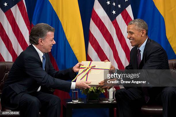 President of Colombia Juan Manuel Santos gives U.S. President Barack Obama a copy of the Colombian peace agreement during bilateral meeting at the...