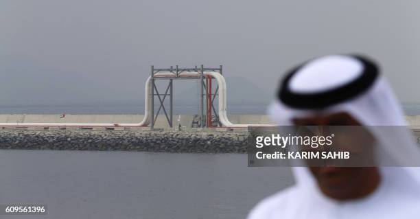 An Emirati man stands in front of a pipeline at the oil terminal of Fujairah during the inauguration ceremony of a dock for supertankers on September...