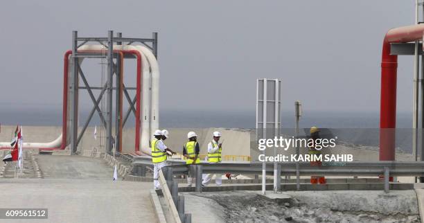 Workers stand next to a pipeline at the oil terminal of Fujairah during the inauguration ceremony of a dock for supertankers on September 21, 2016. -...