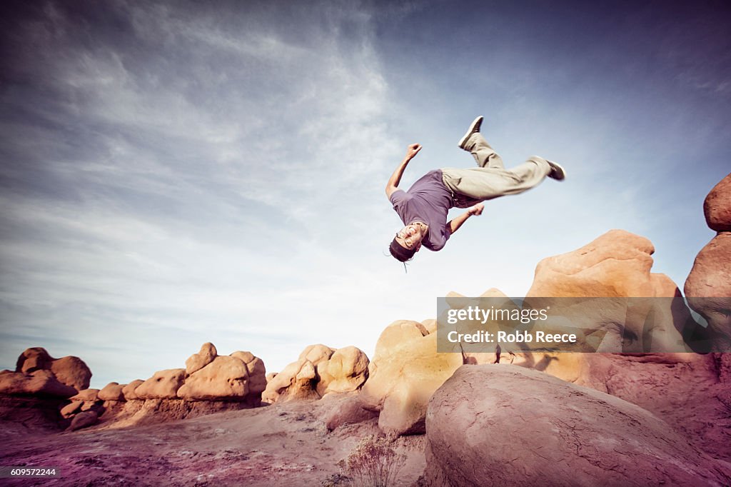 A man performing parkour outdoors on rock formations in the desert