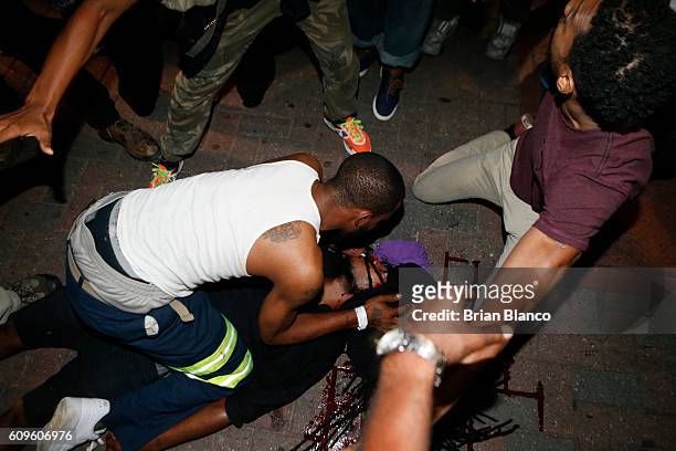 Protesters tend to a seriously wounded protester in the parking area of the the Omni Hotel during a march to protest the death of Keith Scott...