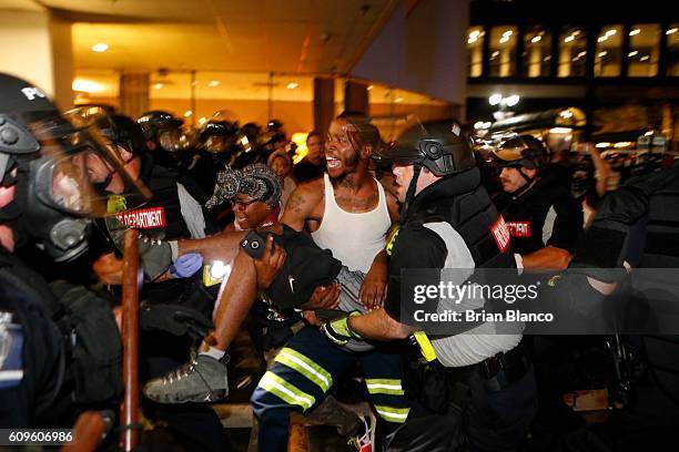 Police and protesters carry a seriously wounded protester into the parking area of the the Omni Hotel during a march to protest the death of Keith...